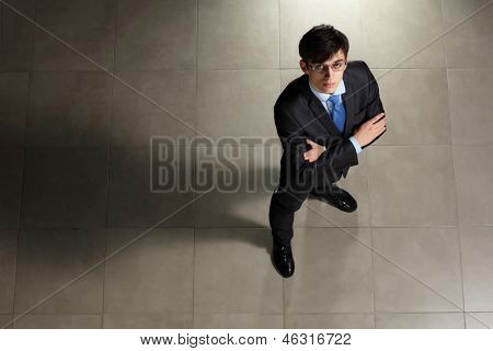 Image of young businessman in glasses arms crossed. Top view
