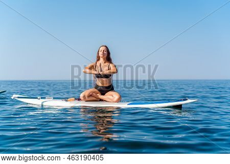 Sporty Girl On A Glanders Surfboard In The Sea On A Sunny Summer Day. In A Striped Swimsuit, He Sits