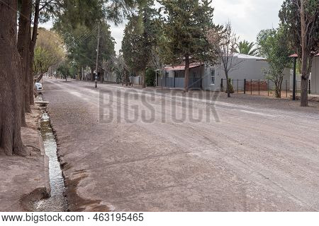 Loxton, South Africa - Sep 2, 2022: A Gravel Street Scene, With Houses And A Water Canal, In Loxton 