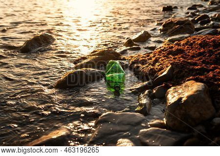 Pollution Of Seas And Rivers. Ecosystem Conservation. A Green Plastic Bottle Is Lying In The Water O