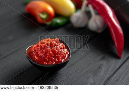 Hot Chili Pepper Paste. Red Sauce On A Wooden Background. Ajika Or Ajika In Georgian Cuisine Or Hari