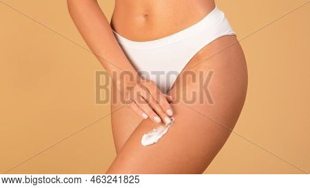 Slim Woman In White Panties Applying Moisturising Body Cream On Her Legs, Using Anti-cellulite Lotio