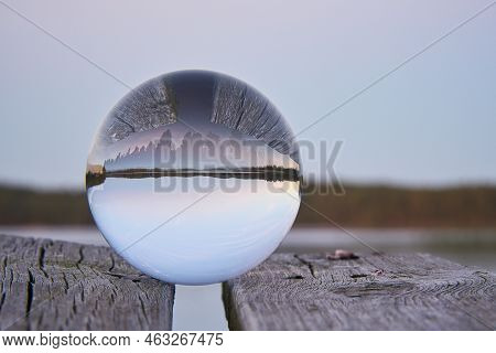 Glass Ball On A Wooden Pier At A Swedish Lake At Evening Hour. Nature Shot From Scandinavia