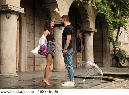 Young Couple Dancing Under Rain On City Street