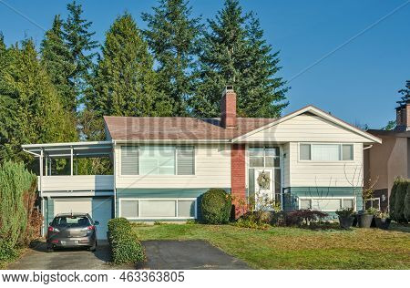 Inexpensive Residential House With Grey Car Parked On The Driveway.