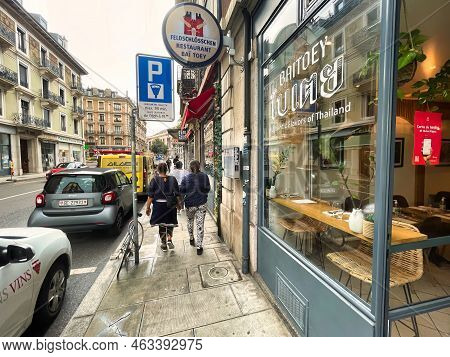 Geneva, Switzerland - September 15 2021: Two People Are Walking On The Sidewalk Passing By The Front