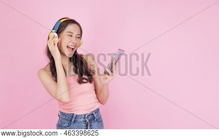 Charming Asian Woman Wear Headphones Holding Mobile Phone Listen Music Song Mood Enjoy On Pink Backg