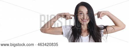 Portrait Of Smiling Woman Puts Fingers In Ears. Positive Emotions And Extraneous Noise Concept