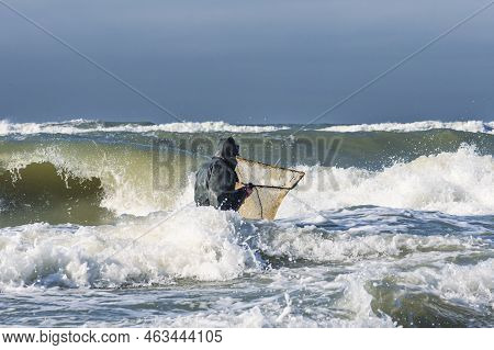 Amber Catching In The Baltic Sea. Amber Catcher Or Fisherman With Fisherman\\\'s Coat And Boots Into