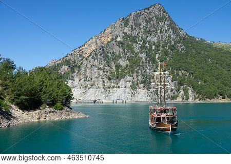 A Three-masted Tourist Yacht Floats On A Lake Among Mountain Cliffs Near The Oymapinar Dam. Green Ca