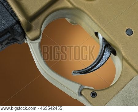 Assault Rifle Trigger That Has A Brown Background Behind