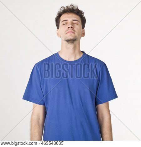 Standing Young Man In Blue Shirt Closing Eyes