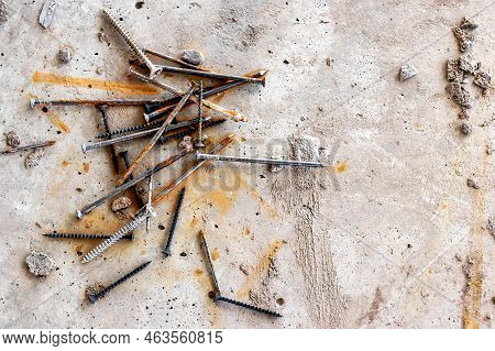 Nails And Self-tapping Screws On Concrete At A Construction Site. Rust Streaks On A Concrete Surface