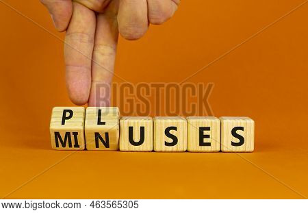 Pluses And Minuses Symbol. Businessman Turns Wooden Cubes And Changes The Word 'minuses' To 'pluses'