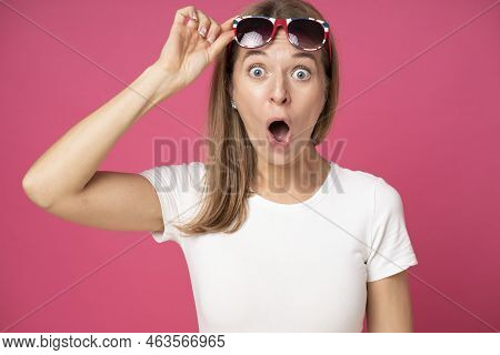 Impressed Shocked Young Attractive Woman Dressed In White T-shirt And Holding Sun Glasses On Her Hea