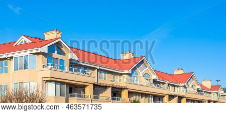 Residential Building With Red Roofs On Blue Sky Background.