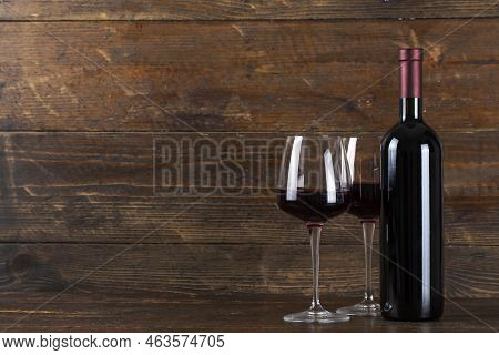 Wine Bottle And Two Glasses On A Wooden Background. Soace For Text.