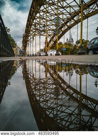 Wroclaw, Poland - September 2021: Beautiful Old Zwierzyniec Bridge Reflected In Puddle At Cloudy Day