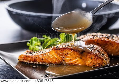 The Spoon Finishes The Portion By Pouring A Demiglas Sauce Over The Salmon Fillets.