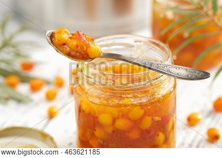 Jar Of Healthy Sea Buckthorn Jam. A Spoonful Of Buckthorn Jam Close Up. A Pot, Jam Jar And Sea Buckt
