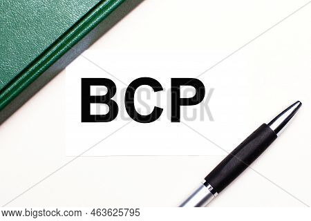 On A Light Gray Background Lies A Pen, A Green Notebook And A White Card With The Text Bcp Business 