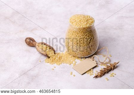 Traditional Dry Pearl Couscous In A Glass Jar On A Light Background. Selective Focus.