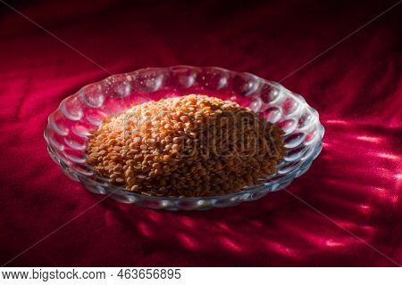Raw Uncooked Masur Dal Or Lentil On A Decorated Glass Plater Placed On Red Table Cloth