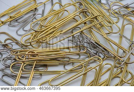Gold And Silver Colourd Paper Clips In A Pile On A White Background.