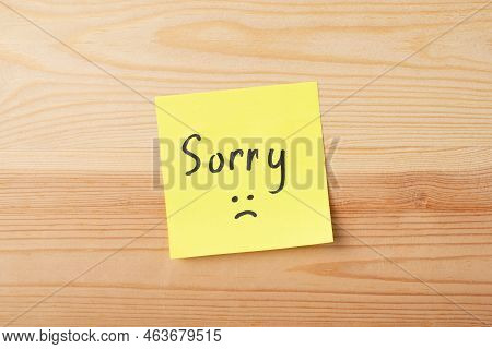 Yellow Sticky Note With Inscription Sorry On Wooden Table