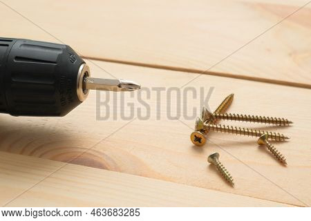 Table With Tool. Electric Screwdriver On A Wooden Table. Side View Of The Black Metallic Screws, Ele