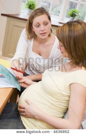 หญิงตั้งครรภ์ในห้องครัวกับเพื่อนอ่านจุลสาร