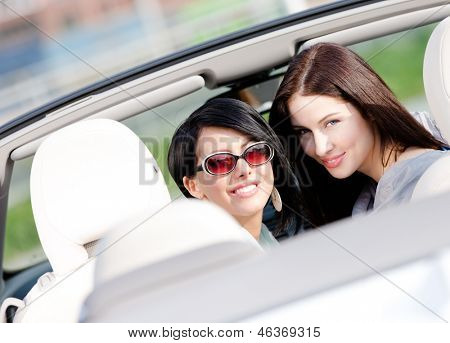 Due ragazze felici seduti nello sguardo cabriolet indietro e divertirsi mentre avendo piccolo viaggio auto