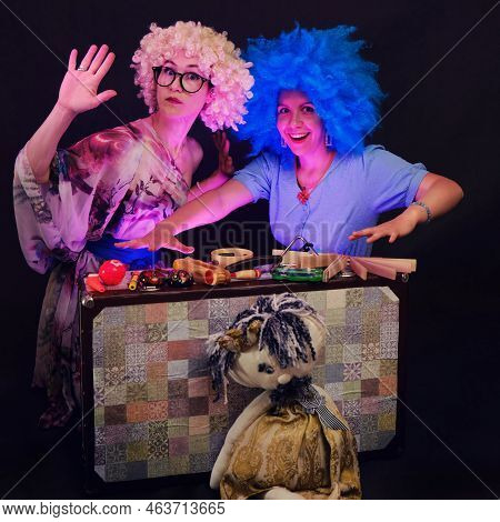 Happy Women In Funny Wigs Give A Musical Performance On A Studio Black Background. Smiling Women Sho