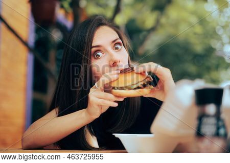 Woman Eating A Burger In A Restaurant For Lunch