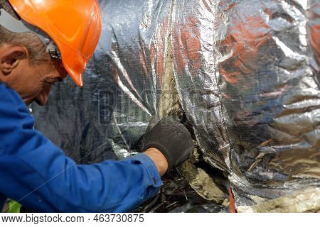 Bucharest, Romania - October 13, 2022: Worker Uses Glass Wool To Thermal Insulate A Hot Water Metall