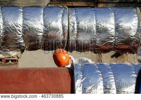 Bucharest, Romania - October 13, 2022: Worker Uses Glass Wool To Thermal Insulate A Hot Water Metall