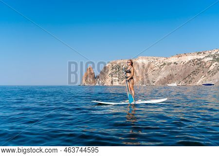 Sporty Girl On A Glanders Surfboard In The Sea On A Sunny Summer Day. Summer Activities By The Sea