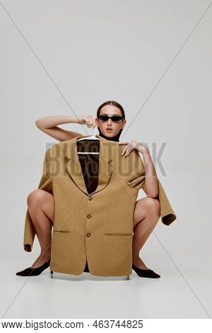 Portrait Of Stylish Young Girl Posing In Trendy Singlasses, Holding Oversized Jacket Isolated Over G