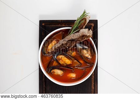 Tomato Soup With Mussels In A White Deep Dish On A Dark Wooden Serving Board. Served With Rye Crouto