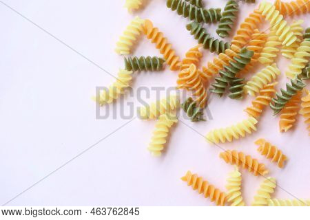 Organic Fusilli Tricolore Spilling On Pink Background