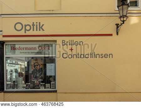 Germany, Wismar - July 13, 2022: Yellow Facade Of Biedermann Optik, Optician Retail Store In Darkwar