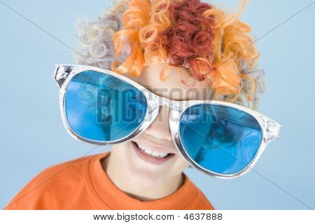 Giovane ragazzo indossa occhiali da sole sorridente e parrucca Clown