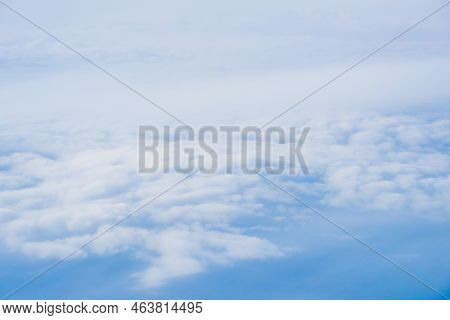 Flying Above The Clouds With Blue Skies In An Airplane Looking Out Of The Window. White Fluffy Cloud