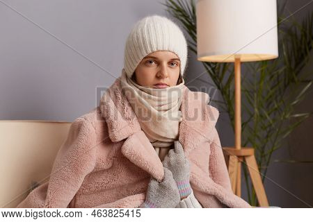 Portrait Of Attractive Caucasian Young Adult Woman Wearing Warm Clothes And Wrapped In Scarf Sitting