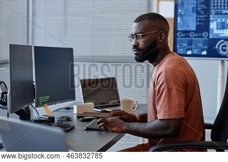 Side View Of Black Software Engineer Using Computer In High Technology Office, Data Systems And Prog