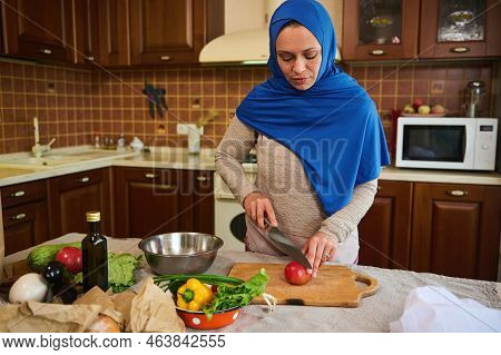 Beautiful Middle-eastern Muslim Woman, Pretty Housewife In Blue Hijab, Chopping Ripe Juicy Tomato On