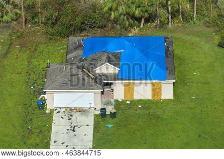 Aerial View Of Damaged In Hurricane Ian House Roof Covered With Blue Protective Tarp Against Rain Wa