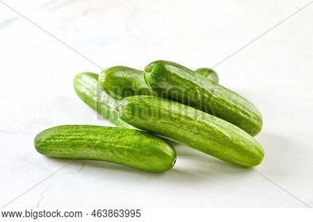 Mini Cucumbers On White Marble, Ready To Cook And Eat
