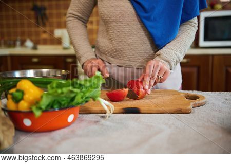 Cropped View: Housewife In Blue Hijab, Using Kitchen Knife, Slicing Tomatoes On A Wooden Cutting Boa