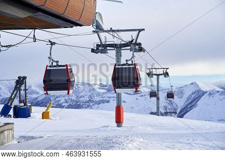 Cable Car Gondola At Ski Resort With Snowy Mountains On Background. Modern Ski Lift With Funitels An